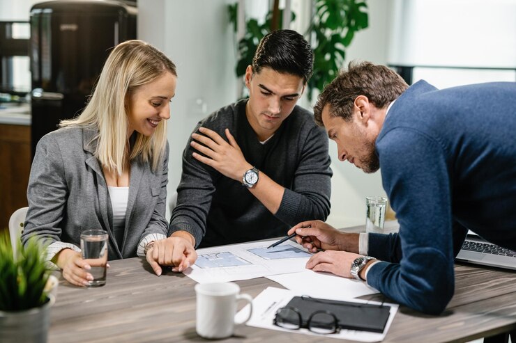 real-estate-agent-and-young-couple-going-through-their-housing-plan-on-a-meeting_637285-3828.jpg